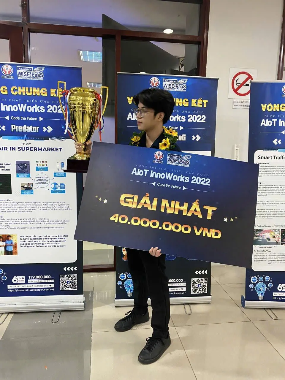 Le Ngoc Gia Huy holding the AIoT InnoWorks 2022 champion trophy and first-prize board